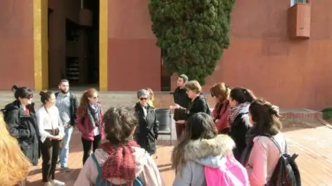 Eine Gruppe von Studentinnumringt eine Rednerin. Sie alle stehen auf einem städtischen Platz, um einen Gender Walk zu starten.